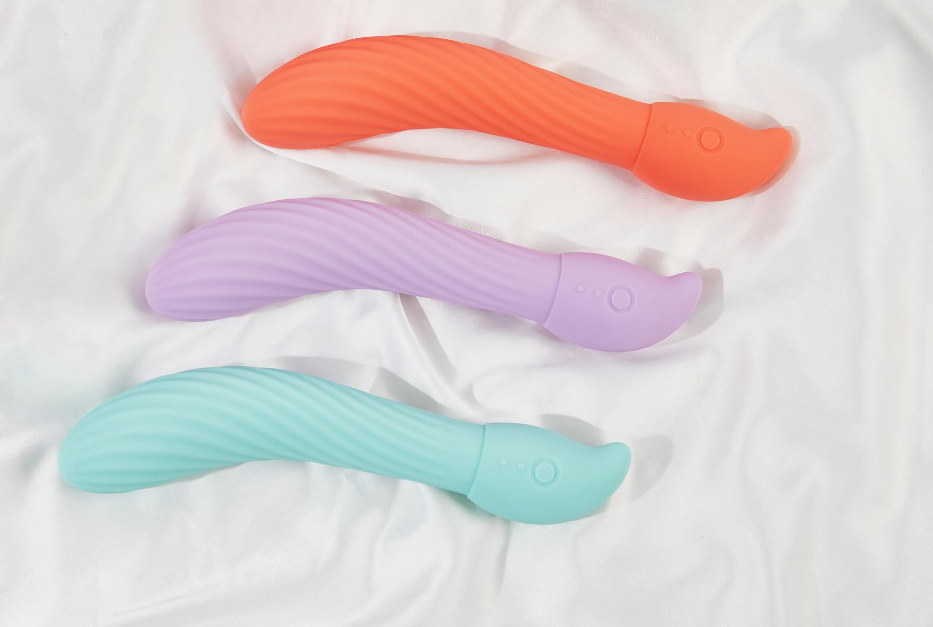 Close-up of colorful vibrators arranged on white fabric, highlighting smooth textures.