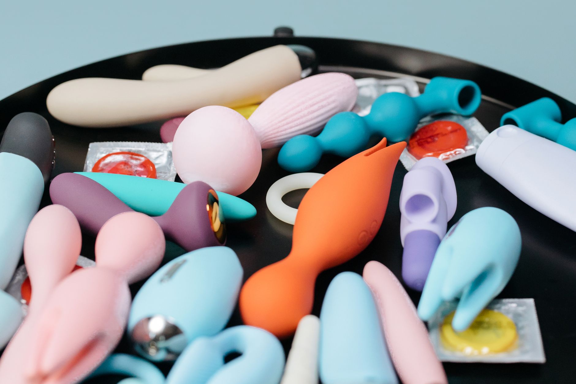 Vibrant collection of various sex toys on a black tray, featuring diverse shapes and colors