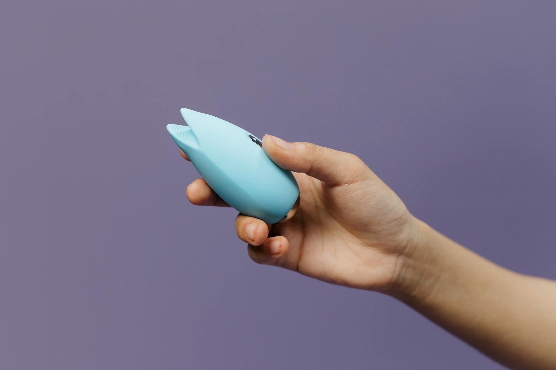 A blue silicone lemon vibrator held in hand against a purple background, promoting self-care and relaxation.